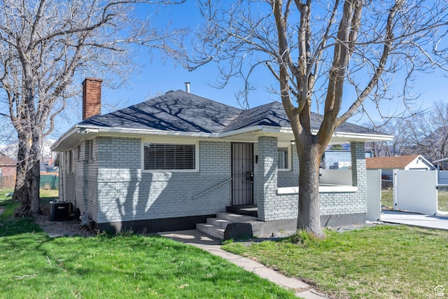 view of front of property with central AC unit, brick siding, a chimney, and a front lawn