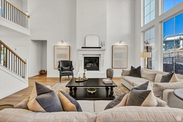 4875 N Vialetto Way, Lehi, UT 84043 - living area with baseboards, stairway, a high ceiling, wood finished floors, and a glass covered fireplace
