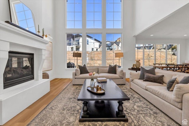 4875 N Vialetto Way, Lehi, UT 84043 - living room featuring a glass covered fireplace, a high ceiling, baseboards, and wood finished floors