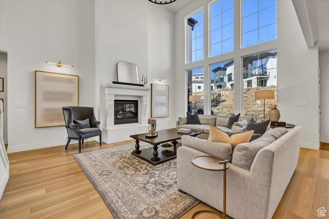 4875 N Vialetto Way, Lehi, UT 84043 - living room featuring baseboards, a high ceiling, a glass covered fireplace, and light wood finished floors