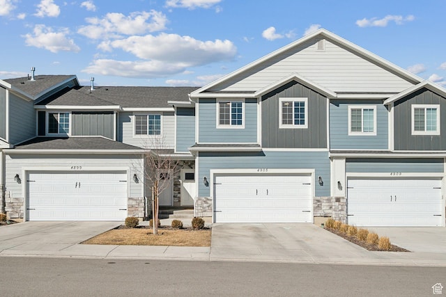 townhome / multi-family property featuring stone siding, board and batten siding, and concrete driveway