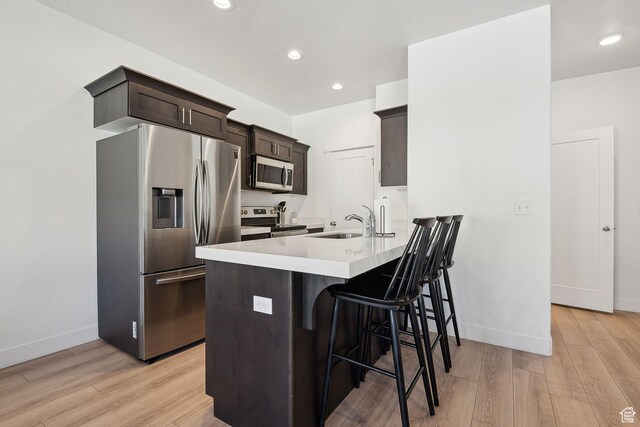 4905 E Lake Corner Dr, Eagle Mountain, UT 84005 - kitchen with a sink, dark brown cabinetry, appliances with stainless steel finishes, a breakfast bar area, and light wood finished floors