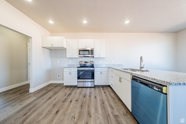 4377 E Colt Cir, Kanab, UT 84741 - kitchen with light wood-style flooring, a sink, stainless steel appliances, a peninsula, and white cabinets