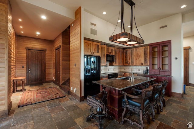 8376 E Aspen Rdg Unit 44, Heber City, UT 84032 - kitchen with black appliances, stone tile floors, a kitchen bar, backsplash, and an island with sink