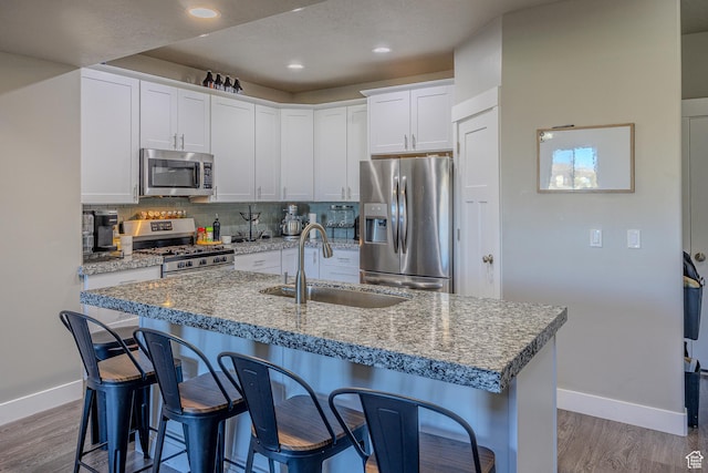 1997 E Abbey Way S, Eagle Mountain, UT 84005 - kitchen with a breakfast bar area, wood finished floors, a sink, stainless steel appliances, and tasteful backsplash