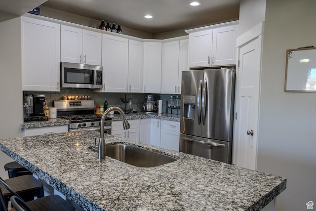 1997 E Abbey Way S, Eagle Mountain, UT 84005 - kitchen featuring a kitchen bar, a sink, backsplash, stainless steel appliances, and white cabinets