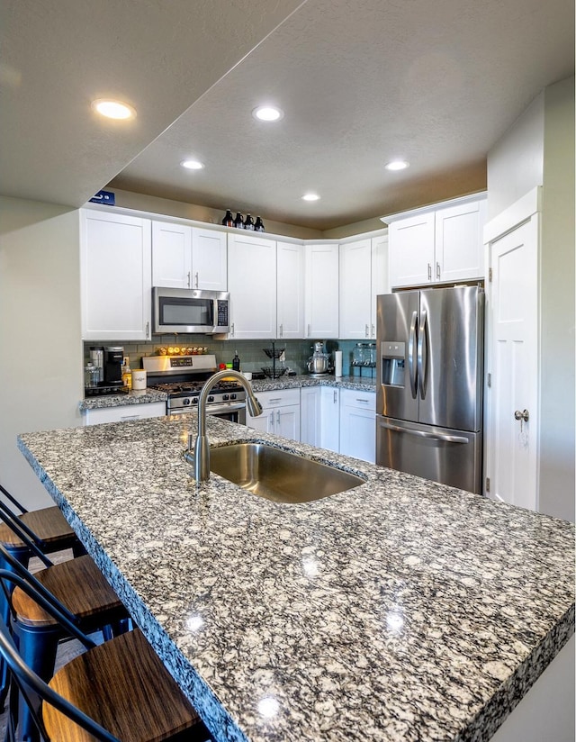 1997 E Abbey Way S, Eagle Mountain, UT 84005 - kitchen with a breakfast bar area, a sink, decorative backsplash, stainless steel appliances, and white cabinets
