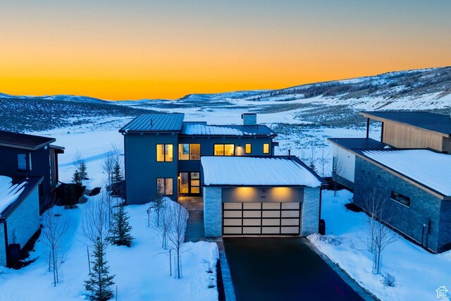 contemporary house with stucco siding, metal roof, and a garage