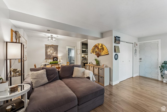 living area featuring light wood-type flooring, baseboards, and visible vents
