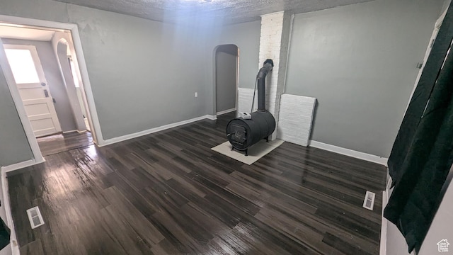 interior space with arched walkways, visible vents, dark wood-type flooring, and baseboards