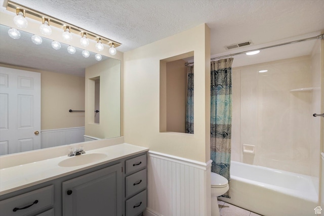 bathroom featuring toilet, shower / bath combo, a textured ceiling, wainscoting, and vanity
