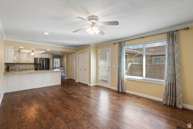 unfurnished living room with ceiling fan, baseboards, a textured ceiling, and dark wood finished floors