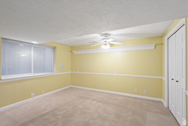 carpeted empty room featuring a ceiling fan, baseboards, and a textured ceiling