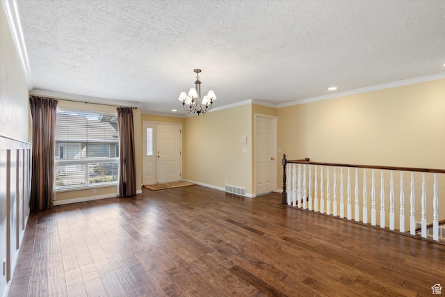 spare room with visible vents, wood finished floors, crown molding, baseboards, and a chandelier