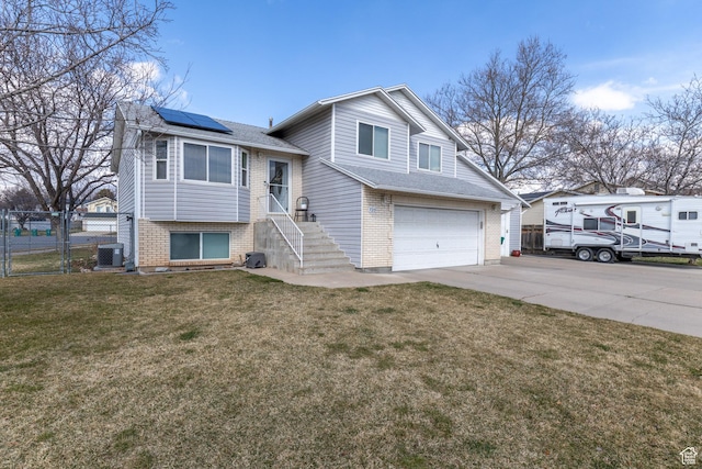 2350 N 720 W, Layton, UT 84041 - tri-level home with concrete driveway, an attached garage, roof mounted solar panels, fence, and brick siding
