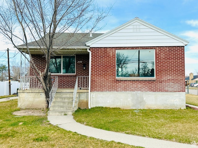 view of front facade featuring a front lawn, covered porch, and brick siding