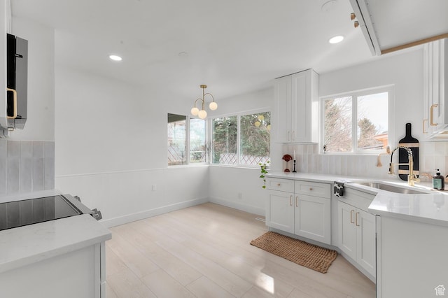 kitchen with backsplash, baseboards, recessed lighting, white cabinetry, and a sink