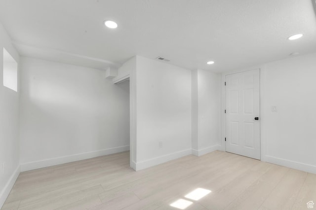 below grade area with light wood-style flooring, recessed lighting, visible vents, and baseboards