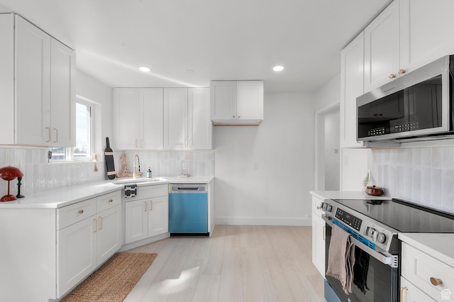kitchen featuring light countertops, decorative backsplash, stainless steel appliances, white cabinetry, and a sink