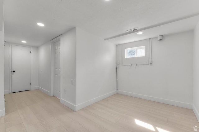 below grade area with recessed lighting, visible vents, light wood-style flooring, and baseboards