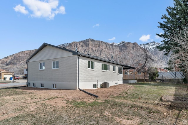 rear view of house featuring brick siding, a mountain view, a lawn, and cooling unit