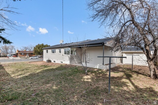 back of house with central air condition unit, a lawn, brick siding, and fence