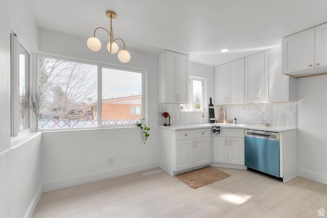 kitchen featuring tasteful backsplash, dishwasher, white cabinets, and light countertops