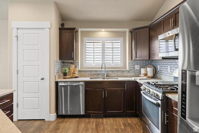 kitchen featuring wood finished floors, a sink, light countertops, dark brown cabinets, and appliances with stainless steel finishes