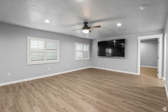 spare room featuring baseboards, a textured ceiling, wood finished floors, and a ceiling fan