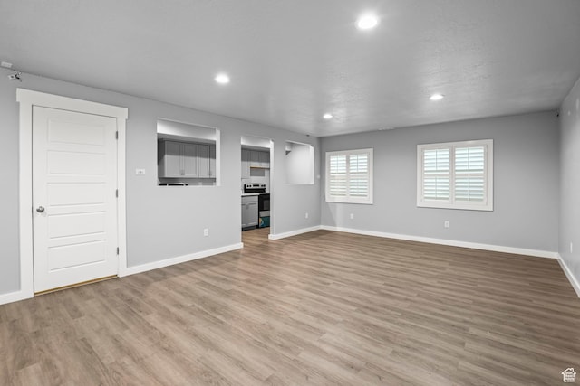 unfurnished living room featuring recessed lighting, baseboards, and wood finished floors