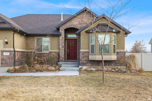 view of front of property with fence, stone siding, and stucco siding