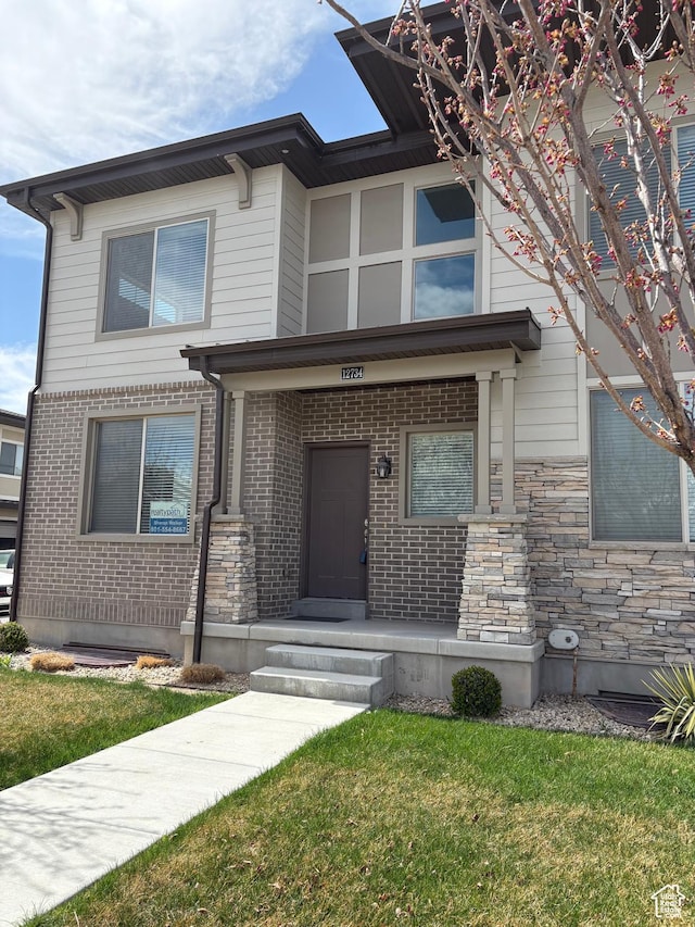 view of front facade with a front yard, stone siding, and brick siding