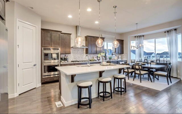 6211 W Wapiti Ridge Ln Unit 332, Herriman, UT 84096 - kitchen with a kitchen bar, a sink, dark wood finished floors, double oven, and wall chimney range hood