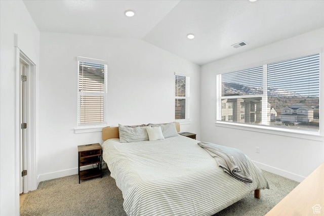 bedroom featuring lofted ceiling, multiple windows, visible vents, and light carpet