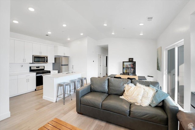 living area with lofted ceiling, recessed lighting, visible vents, and light wood-type flooring