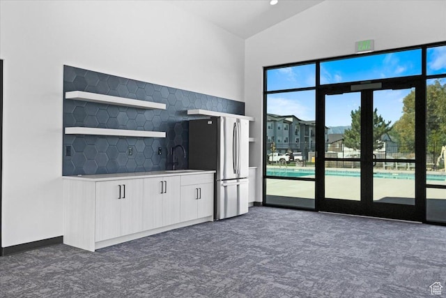 kitchen featuring a sink, freestanding refrigerator, white cabinets, light countertops, and dark colored carpet