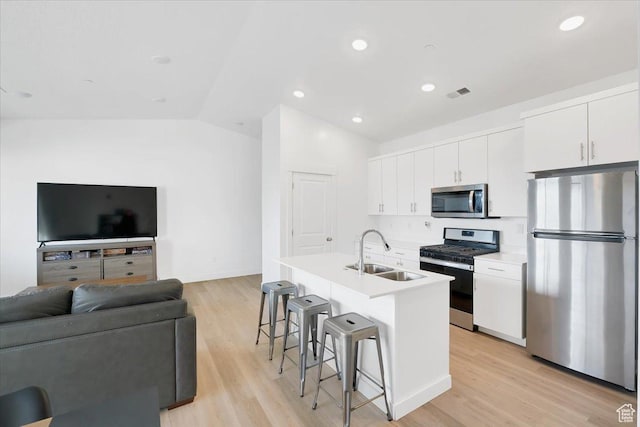 kitchen with visible vents, a sink, white cabinetry, appliances with stainless steel finishes, and a breakfast bar area