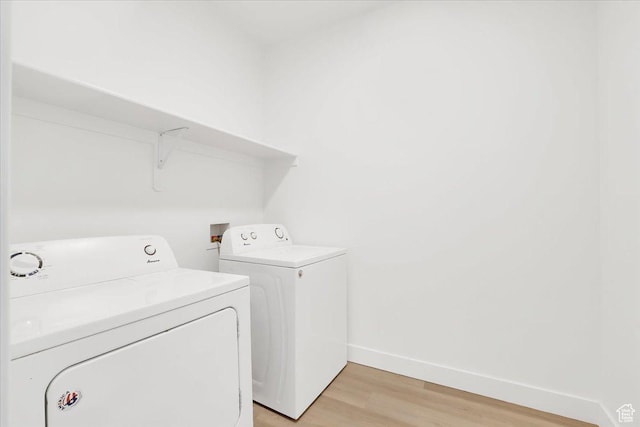 washroom featuring washer and dryer, baseboards, light wood-style floors, and laundry area