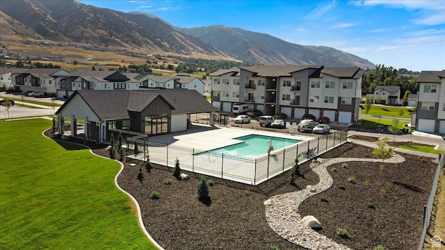 pool featuring a mountain view, fence, a patio area, and a residential view