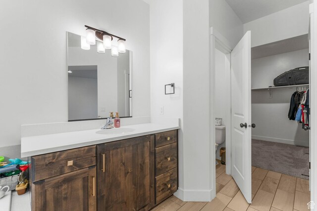 1639 E Yant Flant Dr, St George, UT 84790 - bathroom with a spacious closet, toilet, vanity, and baseboards