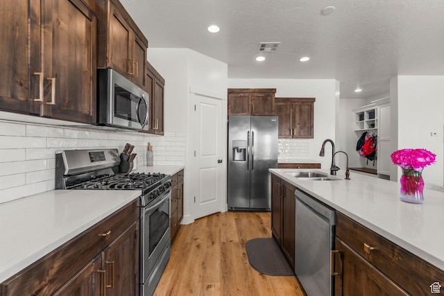 1639 E Yant Flant Dr, St George, UT 84790 - kitchen with a sink, light countertops, dark brown cabinetry, light wood-style floors, and appliances with stainless steel finishes