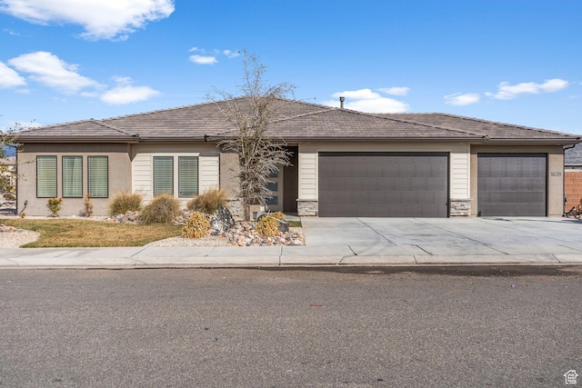 view of front of property with concrete driveway, an attached garage, and stone siding