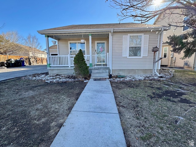 bungalow-style home featuring covered porch and fence