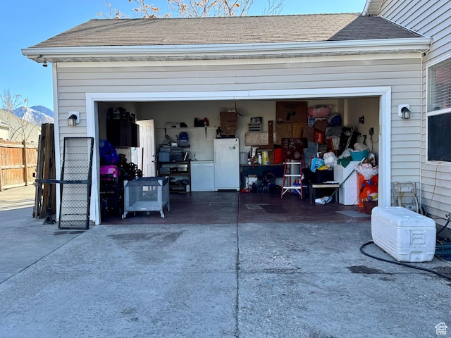173 W Dimaggio Dr N, Tooele, UT 84074 - garage featuring fence, driveway, and freestanding refrigerator