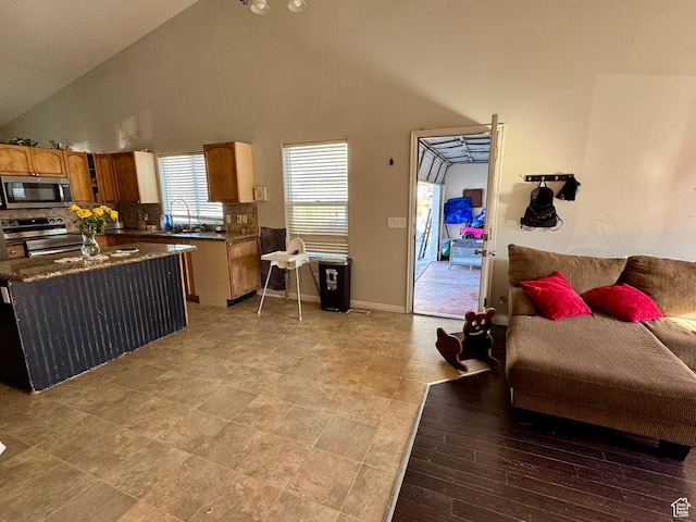 173 W Dimaggio Dr N, Tooele, UT 84074 - kitchen with high vaulted ceiling, a sink, appliances with stainless steel finishes, dark countertops, and backsplash