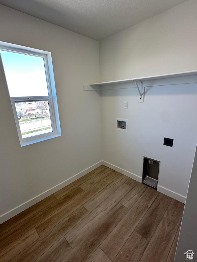 clothes washing area featuring washer hookup, laundry area, baseboards, electric dryer hookup, and wood finished floors
