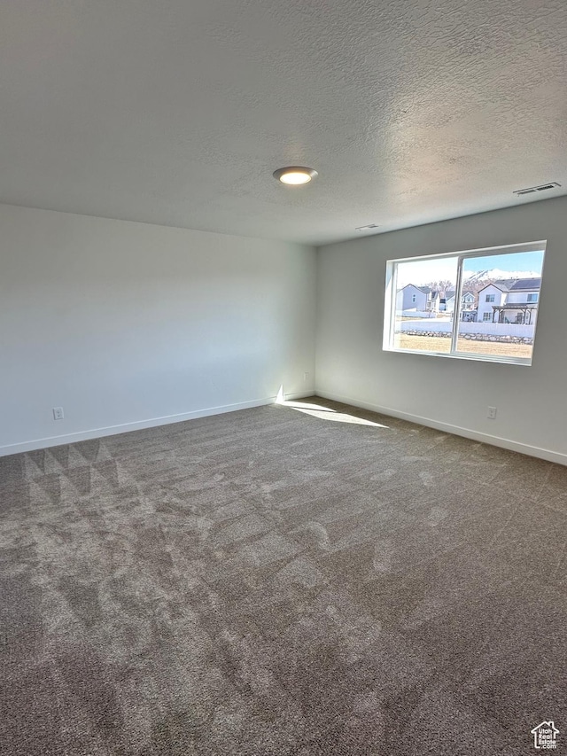 empty room featuring carpet floors, a textured ceiling, and visible vents