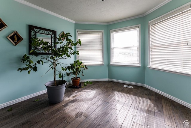unfurnished room featuring visible vents, baseboards, ornamental molding, hardwood / wood-style flooring, and a textured ceiling
