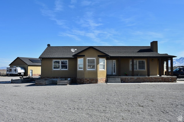 view of front of property with stucco siding, roof with shingles, and a chimney
