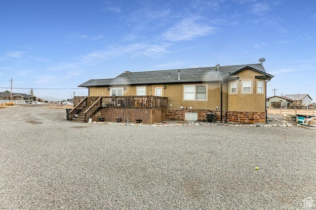 rear view of house with stucco siding, central AC, and a deck